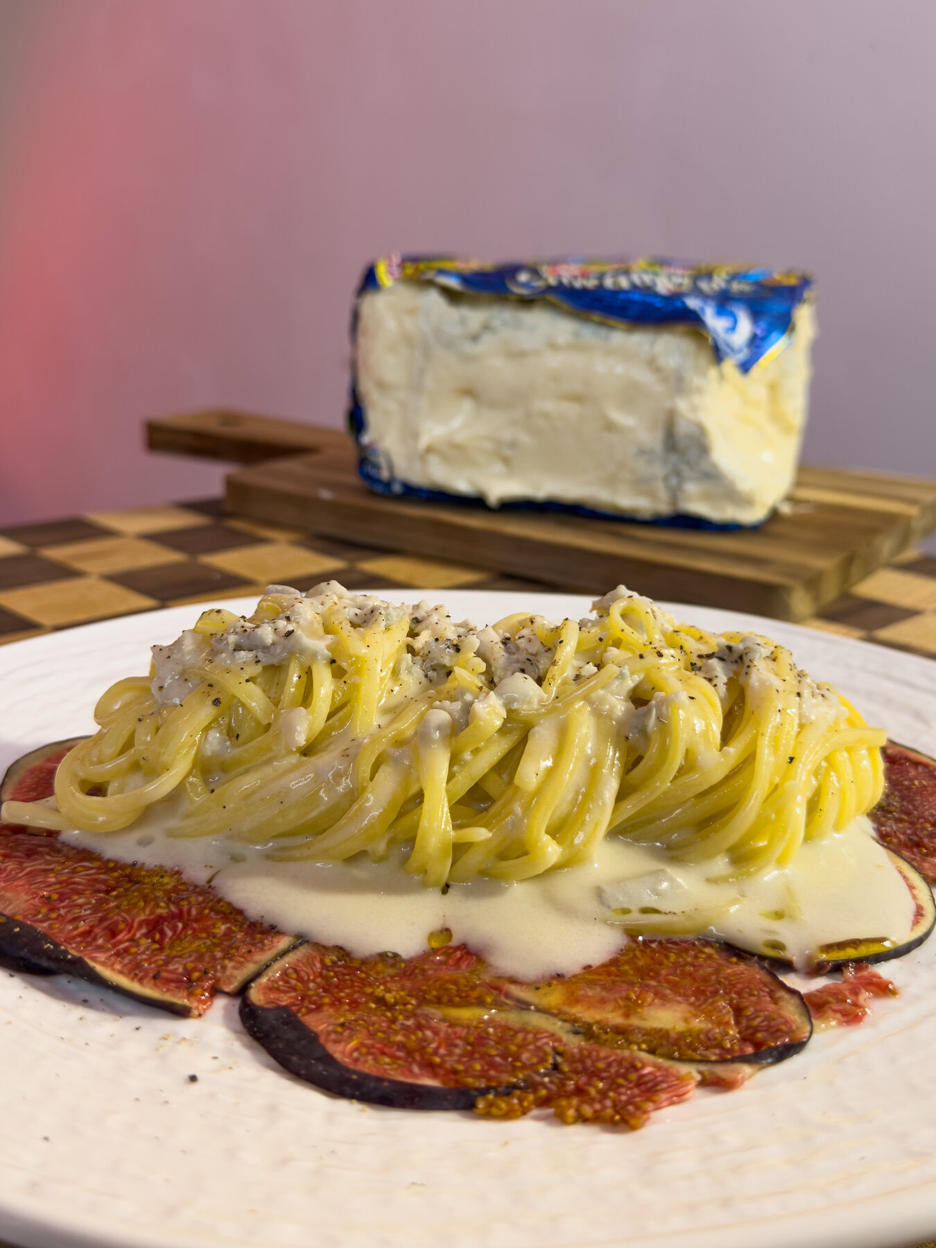 Piatto di pasta con gorgonzola e formaggio, con formaggio Gorgonzola in background, rappresenta il marchio IGOR Gorgonzola, noto produttore di formaggi e sponsor di volley.